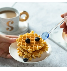 Cucchiaio in vetro resistente al calore che versa sciroppo sui waffle per dessert
