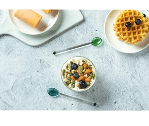 Vista dall'alto di cucchiai colorati in vetro resistente al calore con yogurt e waffle