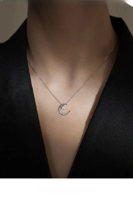 Detail of 925 sterling silver moon and star necklace with white cubic zirconia on black suit