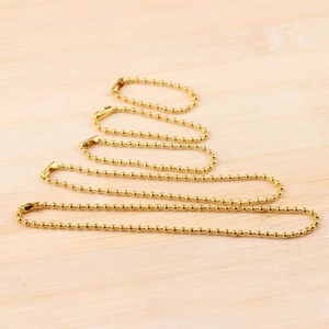 Detail of 3.2mm gold ball chains with connectors arranged on a wooden surface