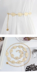 Detail of gold metal leaf waist chain with rose pendant on a white dress