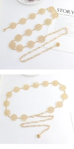 Macro detail of adjustable gold metal chain belt with hollow circular links and floral pendant