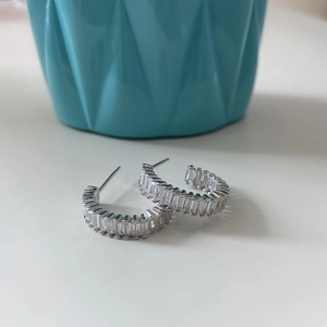 Macro shot of S925 silver C-shape earrings with baguette-cut zircon stones
