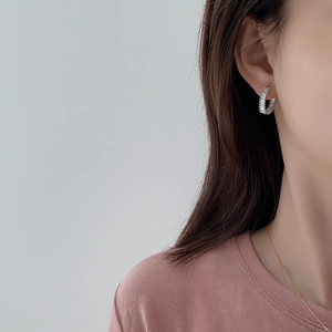 Close-up of S925 silver C-shape earrings with rectangular zircons on model ear