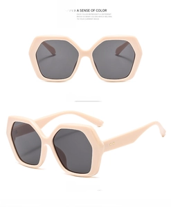 Detail view of large geometric sunglasses with cream frames and dark grey lenses