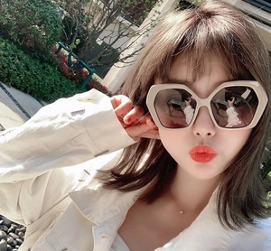 Close-up of stylish oversized beige hexagonal sunglasses with gradient tea lenses on model