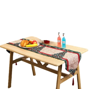 Christmas table runner with tree patterns, red borders and tassels on wooden table