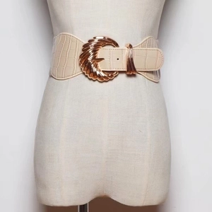 Detail of beige crocodile pattern wide belt with large gold metallic buckle closure