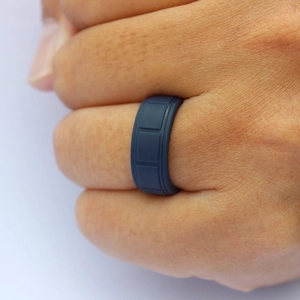 Macro shot of navy blue silicone sports ring with textured checkered pattern on a finger