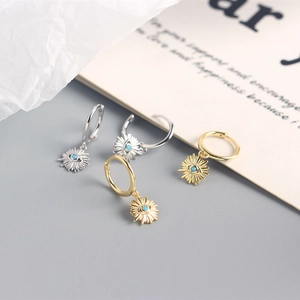 Detailed shot of gold and silver evil eye hoop earrings with turquoise bead on card