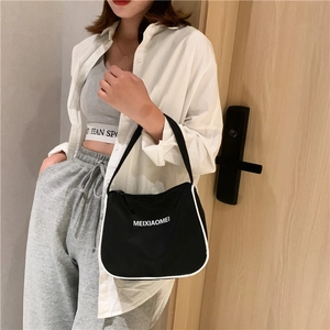 Close-up of black nylon hobo bag with white piping and logo detail on shoulder strap