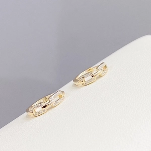 Vista macro de pendientes de aro dorados con diseño de cadena y circonitas brillantes