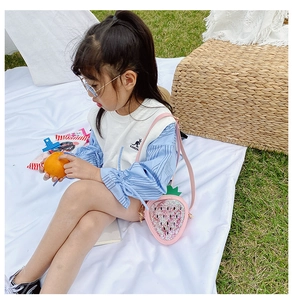 Pink strawberry sequin crossbody bag for girls styled in a scenic outdoor picnic setting
