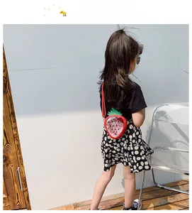 Detailed strawberry sequin crossbody bag shown on model with green leaf top and red strap