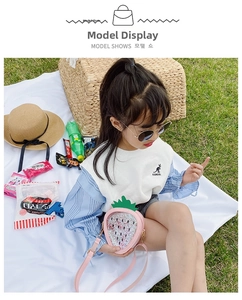 Detail of pink strawberry shape girl's bag with shiny sequins in outdoor picnic setting