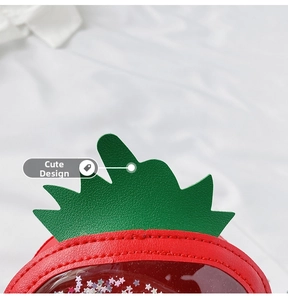 Detail of red strawberry shaped purse with green leaf accent and star sequins