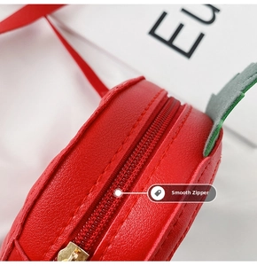 Detail of smooth metal zipper on strawberry shaped red leather bag for kids