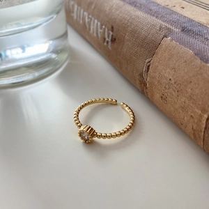 Detail of minimalist 925 silver beaded gold ring with single zircon on vintage book