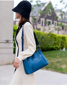 Outdoor shot showing a blue waterproof nylon crossbody bag with black shoulder strap