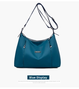 Detail shot of the durable navy blue nylon crossbody bag featuring a metal nameplate