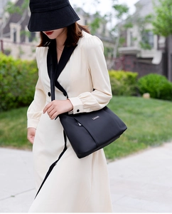 Outdoor lifestyle shot of a black Oxford cloth crossbody bag with adjustable strap