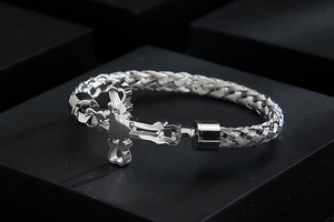 Macro view of silver stainless steel cross bracelet with woven metal chain texture