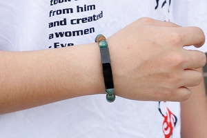 Detail of colorful stone bead bracelet with a black metal ID tag on a person's wrist
