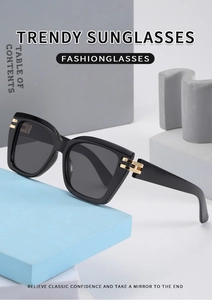 Close-up of square black sunglasses with gold metal hinges and dark polarized lenses
