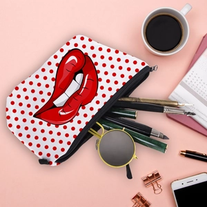 Polka dot cosmetic bag with red lip print styled with office accessories on pink background