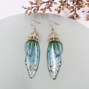 Detailed view of cicada wing earrings with green gradient, gold foil, and crystal accent