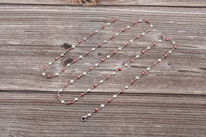 Détail d'une chaîne argentée avec perles œil grec rouge et petits pendentifs en forme de cœur