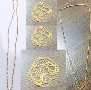 Primer plano de collar de cadena de bolas doradas de acero sobre fondo de madera