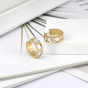 Detail of 18k gold huggie earrings featuring three sparkling heart-shaped zirconia stones
