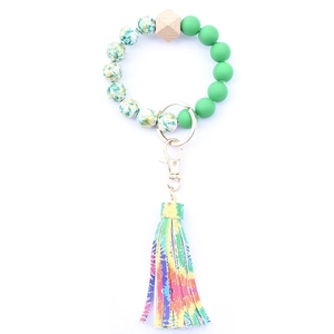 Detail of beaded key ring with green beads, wooden hex bead and colorful tie-dye tassel