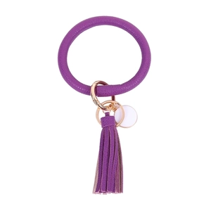 Close-up of purple leather keychain with tassel and rose gold ring on white background