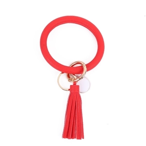 Detail of red pebbled PU leather bracelet keychain with tassel and gold spring clasp