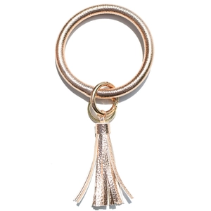 Close-up of rose gold leather tassel keychain wristlet with metallic finish and keyring