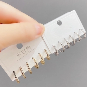 Macro shot of micro-paved cubic zirconia C-shaped huggie earrings in gold and silver