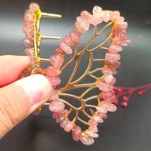 Close-up of golden butterfly hair claw clip with pink natural crystal gravel stones