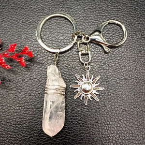 Detail of natural crystal sun keychain with silver wire-wrapped stone on black leather