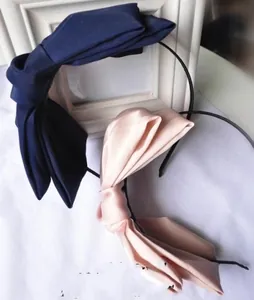 Detail of oversized satin double bow headbands in navy blue and soft pink colors