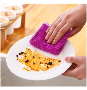 Absorbent purple microfiber cloth cleaning oil and stains from a white ceramic dish