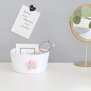 Detail of white cotton rope basket with pink flower decor and eyeglasses for desk storage
