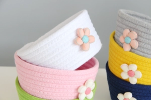 Close-up of woven cotton rope storage baskets with 3D floral accents in multiple colors