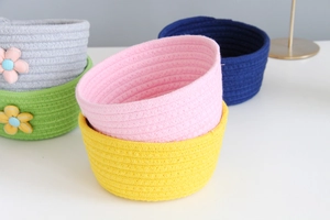 Close-up of stacked colorful cotton rope storage baskets with decorative flower details