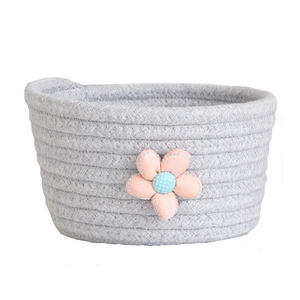 Close-up of grey cotton rope woven storage basket with blue and pink fabric flower details
