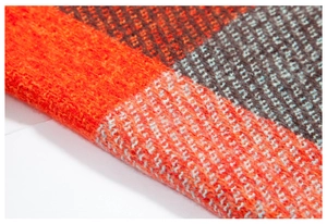 Détail de tissu d'écharpe en tricot doux montrant des motifs à carreaux orange et marron