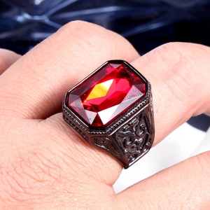 Close-up of vintage men's steel ring with large red gemstone and ornate engraving