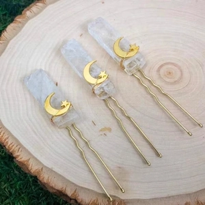 Handmade amethyst crystal hair pins with gold moon and star charms on natural wood surface