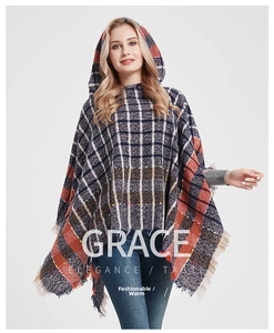 Macro detail of plaid hooded poncho featuring soft textured knit and tassel edge trim